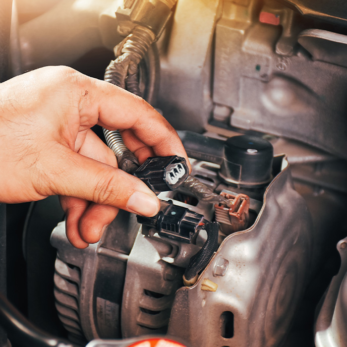 The auto mechanic hand is grasping the car alternator charger plug