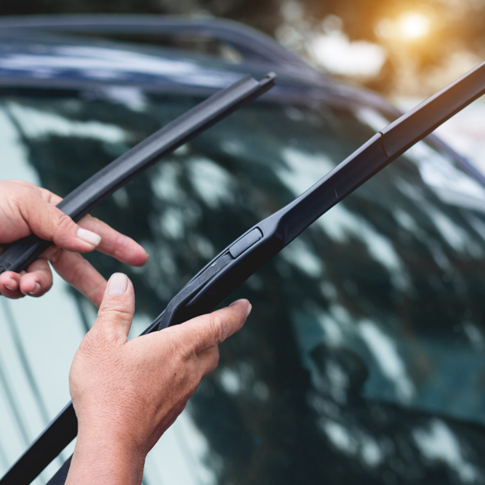 Mechanic replace windshield wipers on car