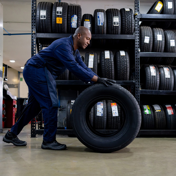 Mechanic changing a flat tire and carrying a wheel at a repair garage