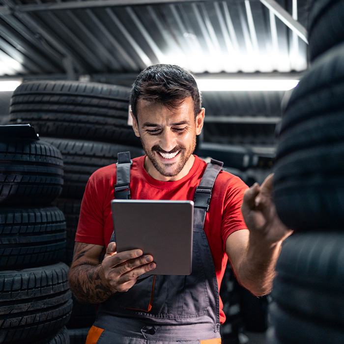 Warehouse worker holding tablet computer, checking inventory and searching for new tire