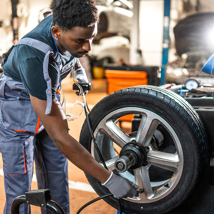 Mechanic balancing car wheel on machine in auto repair shop