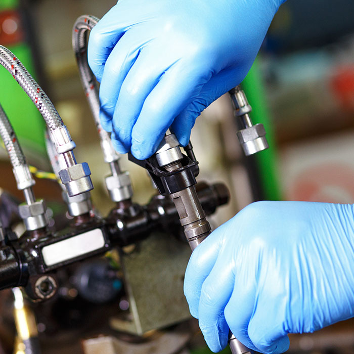 Professional mechanic testing diesel injector in his workshop